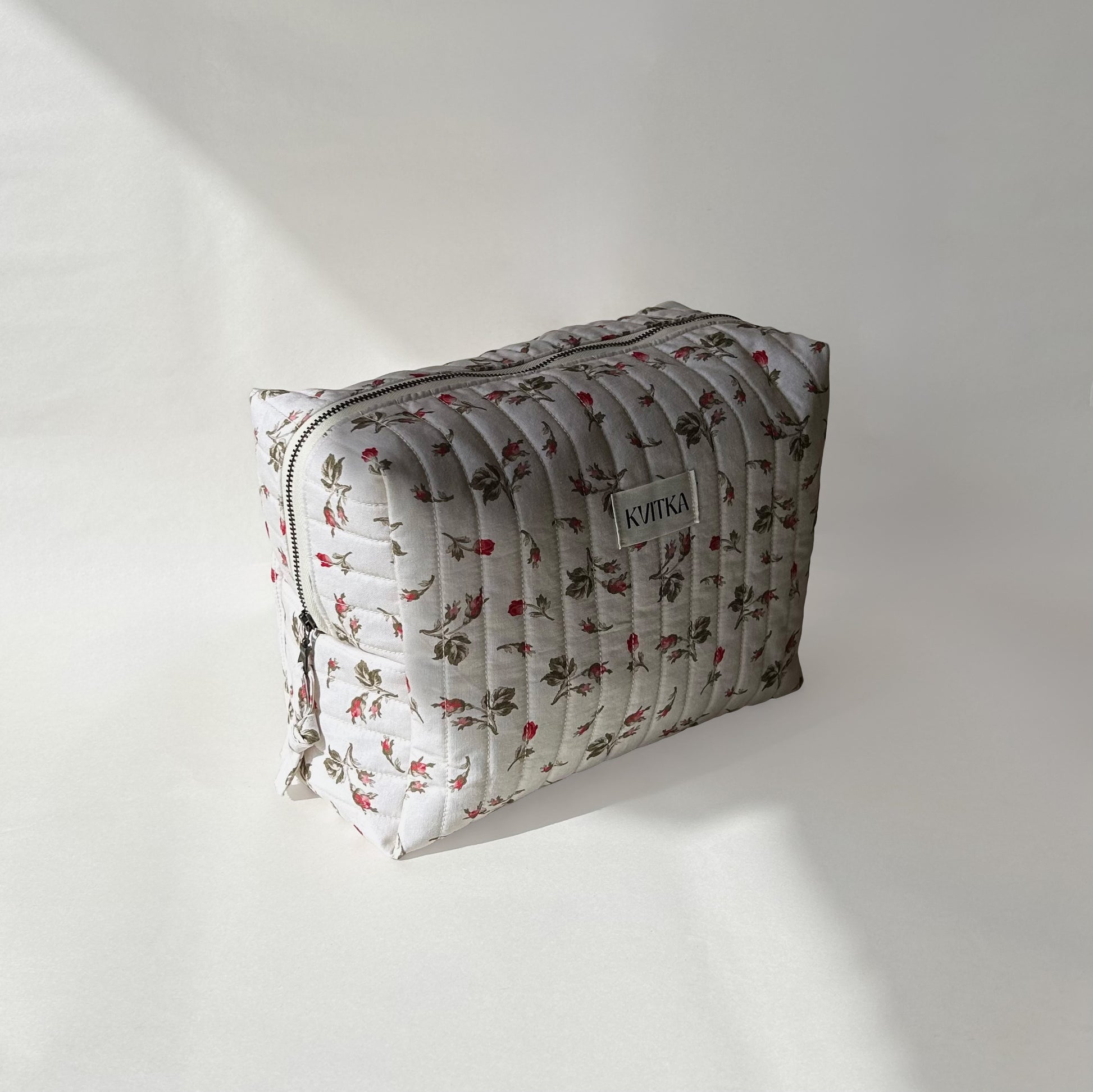 Large-size of quilted makeup bag from the Bell Pivoines collection, angled to the left view to display zip with a zip pull, on a soft white background.