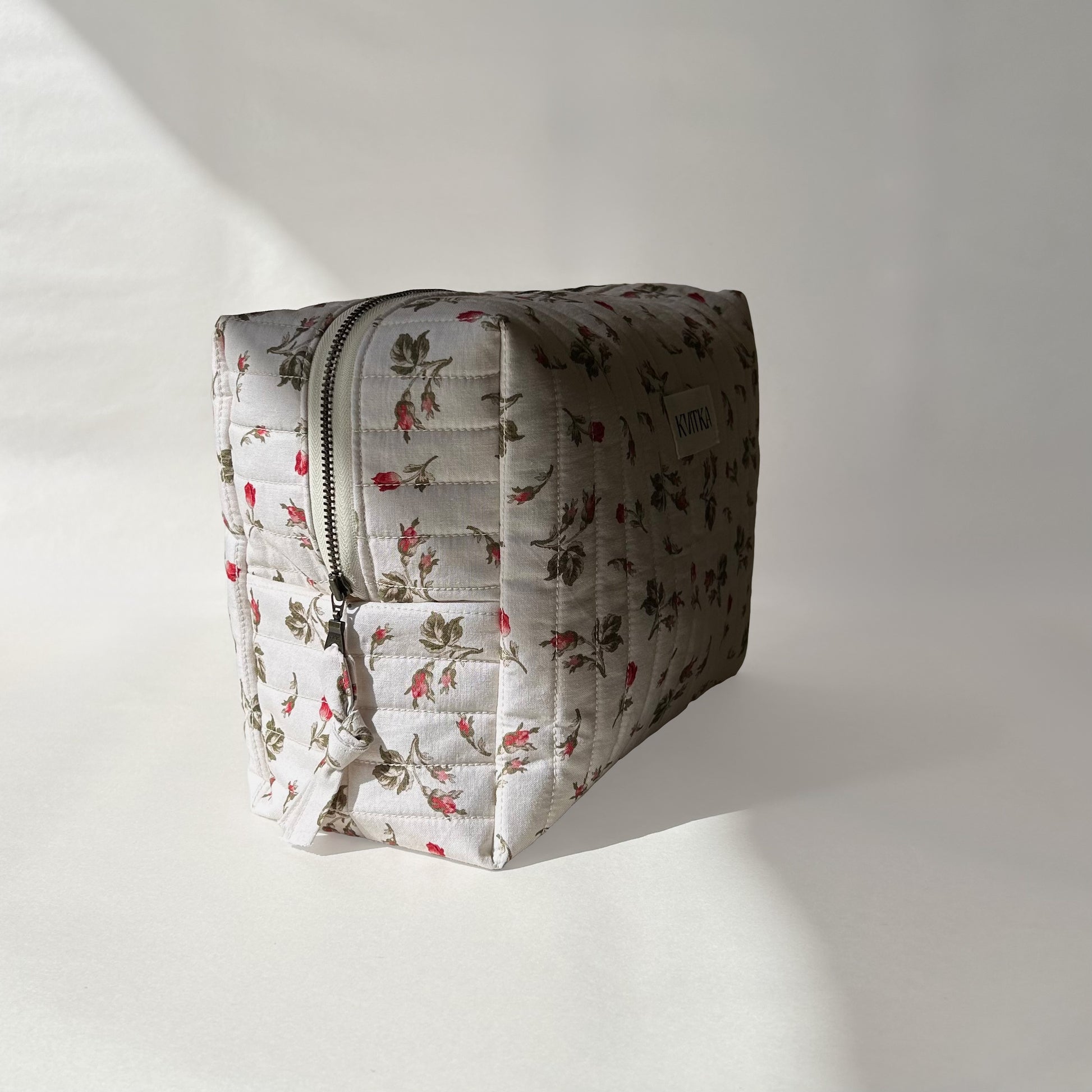 Large-size of quilted makeup bag from the Bell Pivoines collection, angled to the left view to display zip with a zip pull, on a soft white background.