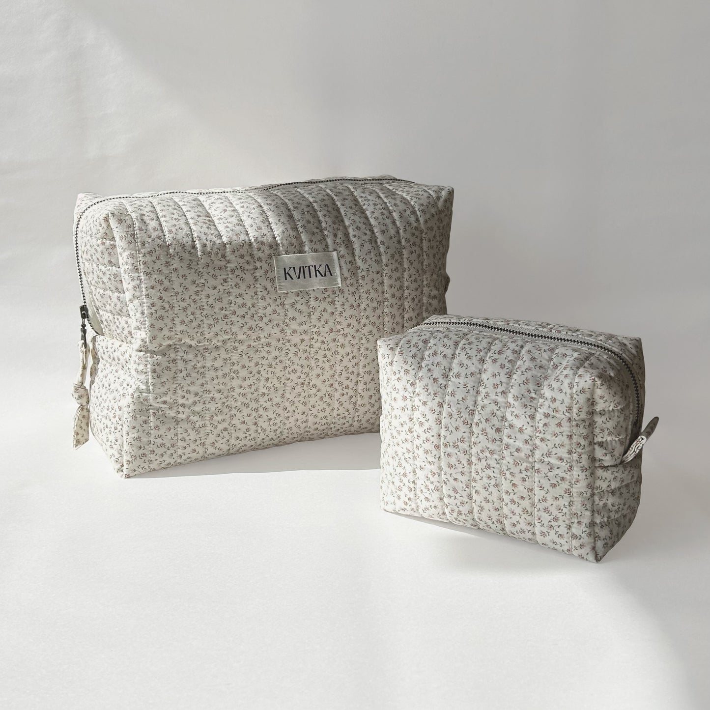 Large and mini-sizes of quilted makeup bags from the Ditsy Blossom collection, displayed at an angle on a soft white background.
