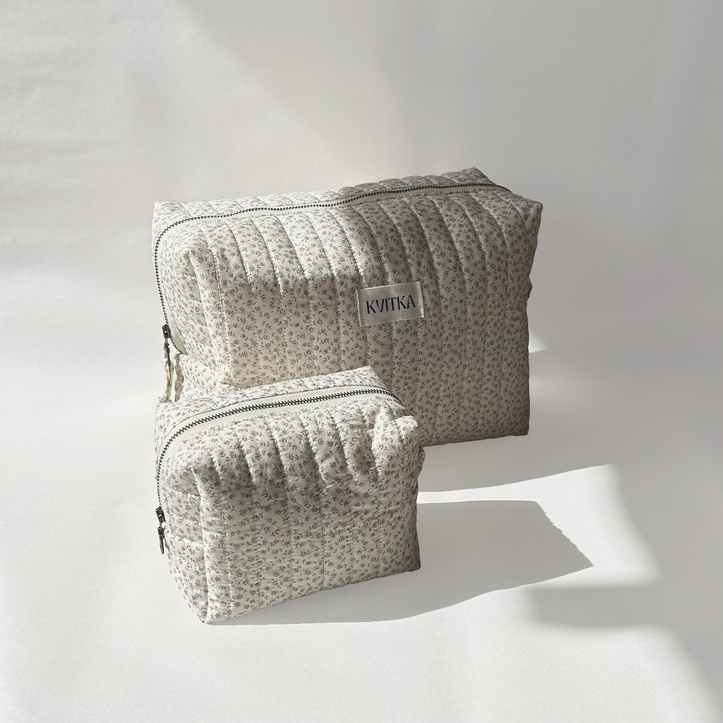 Large and mini-sizes of quilted makeup bags from the Ditsy Blossom collection, angled to the left view on a soft white background.