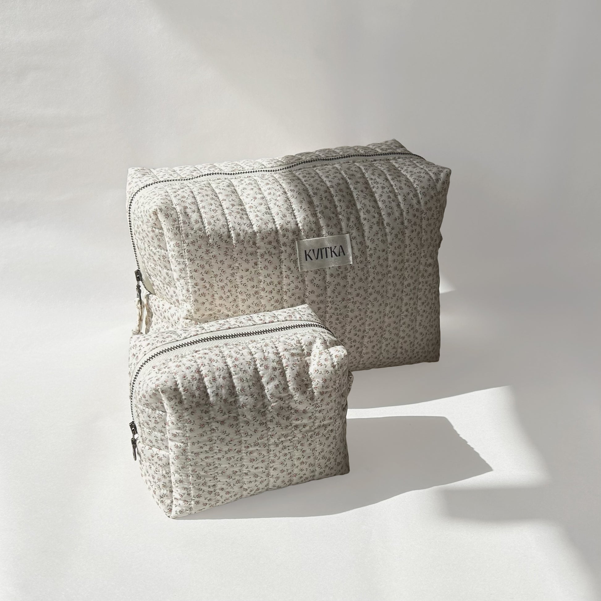 Large and mini-sizes of quilted makeup bags from the Ditsy Blossom collection, angled to the left view on a soft white background.