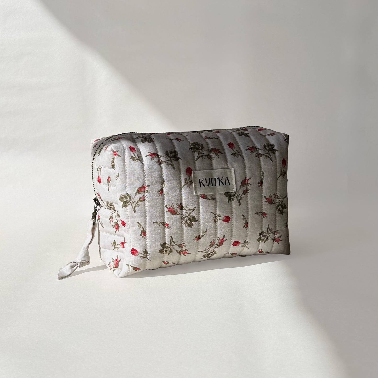 Medium-size of quilted makeup bag from the Bell Pivoines collection, angled to the left view to display zip with a zip pull, on a soft white background.