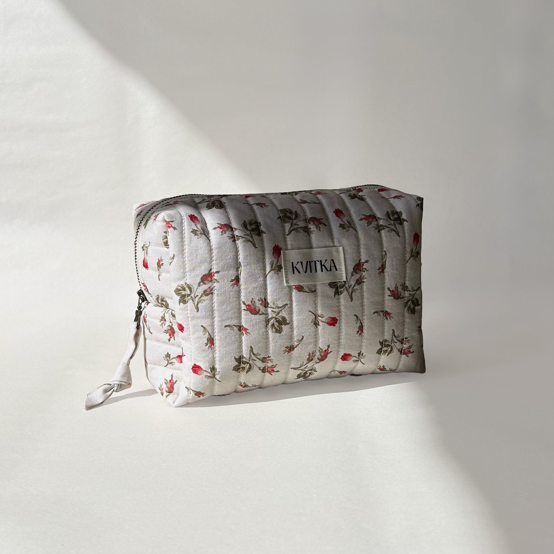 Medium-size of quilted makeup bag from the Bell Pivoines collection, angled to the left view to display zip with a zip pull, on a soft white background.