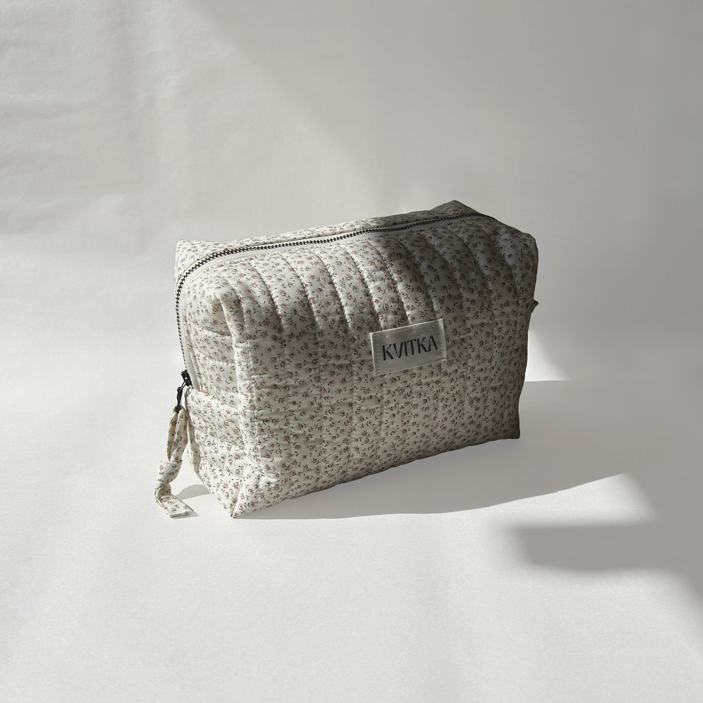 Medium-size of quilted makeup bag from the Ditsy Blossom collection, angled to the left view to display zip with a zip pull, on a soft white background.