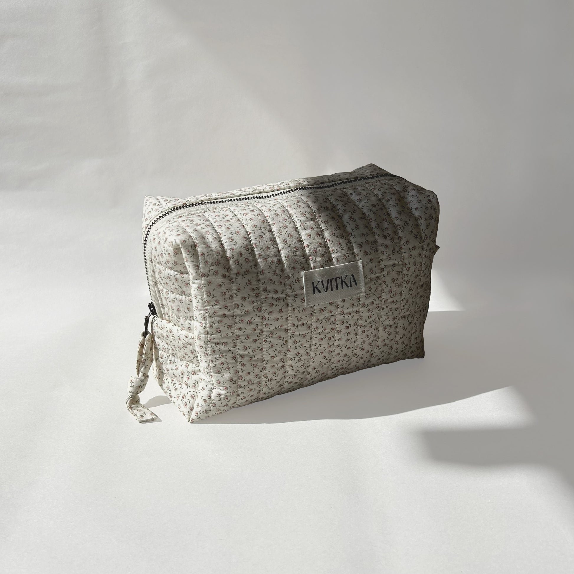Medium-size of quilted makeup bag from the Ditsy Blossom collection, angled to the left view to display zip with a zip pull, on a soft white background.