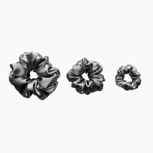 Set of tree silver satin scrunchies from Pebble Satin collection in varying sizes like small, medium and large, displayed in a row on a white background.