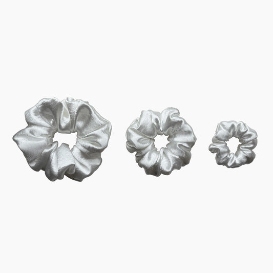 Set of tree white satin scrunchies from Pebble Satin collection in varying sizes like small, medium and large, displayed in a row on a white background.