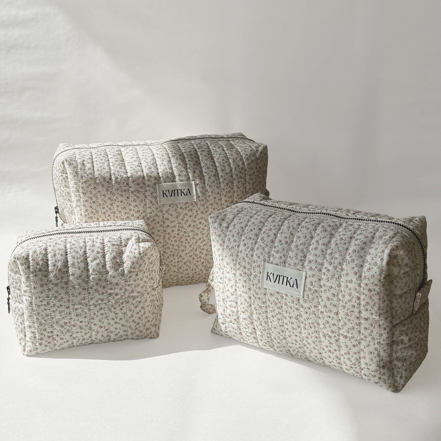 Set of three quilted makeup bags from the Ditsy Blossom collection, shown in mini, medium, and large sizes, displayed at an angle on a soft white background.