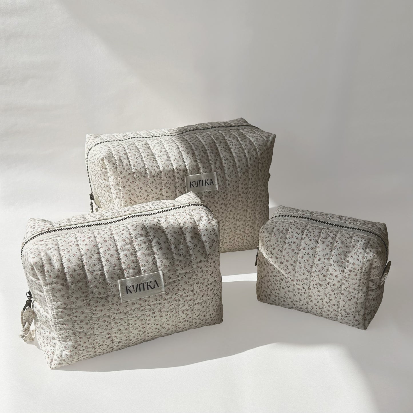 Set of three quilted makeup bags from the Ditsy Blossom collection, shown in mini, medium, and large sizes, displayed at an angle on a soft white background.