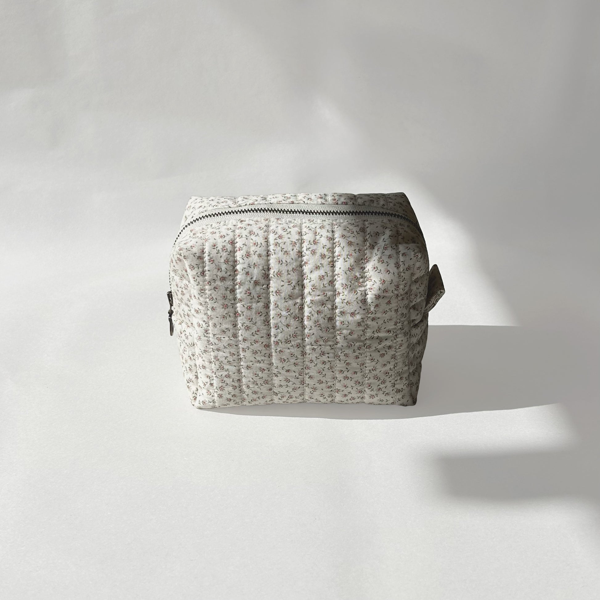 Mini-size of quilted makeup bag from the Ditsy Blossom collection, displayed front-on view on a soft white background.